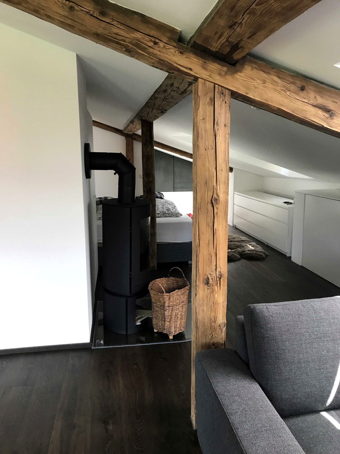 Wohnbereich mit Holzstütze, Kaminofen und Durchblick zum Bett